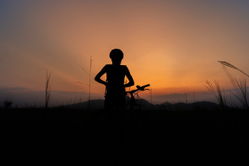 Fototapeta na wymiar A woman riding a bicycle silhouette At the sunsets, relax at the end of the day