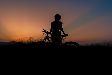A woman riding a bicycle silhouette At the sunsets, relax at the end of the day