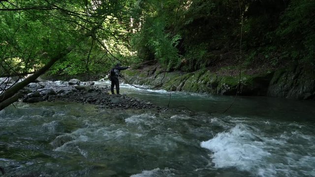 渓流にてフライフィッシングで川魚を釣る