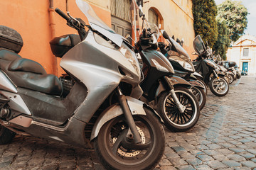 Fototapeta na wymiar Many motor scooters parked on old Rome street, Italy .