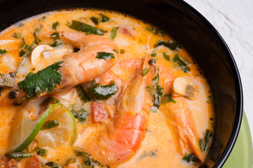  famous delicious Thai Tom yum spicy soup with shrimps and coconut milk on black table. close up