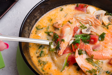   famous delicious Thai Tom yum spicy soup with shrimps and coconut milk on white table. close up