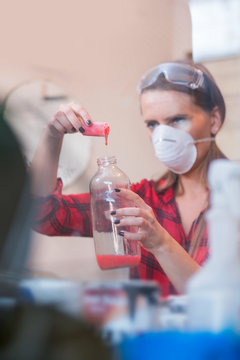 Young Woman Mixing Chemicals In Illegal Laboratory