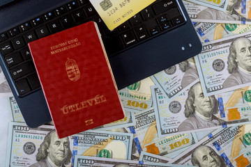 The Hungarian passports of one hundred dollar bills money on laptop keyboard shopping using credit card buy plane tickets