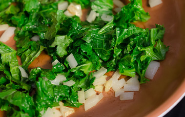 Fresh chopped organic super food Kale leaf and onion being sauteed.  Homegrown vegetables from vegetable garden. Delicious nutritious healthy leaf vegetable of dark greens with onion. 