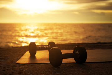 Dumbbell exercise on beach during sunset at the seaside. healthy concept and workout.