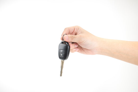 A Hand Holding A Car Key On A White Background