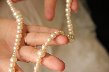 female hands hold pearl beads. On her hands scars from burns