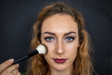 Obraz premium Portrait, beautiful girl, make-up, with smile posing on black background, makeup, powder, eye shadow, mascara, lipstick, eyeshadow