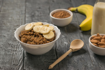 Quinoa porridge with banana and almond milk on a wooden table.