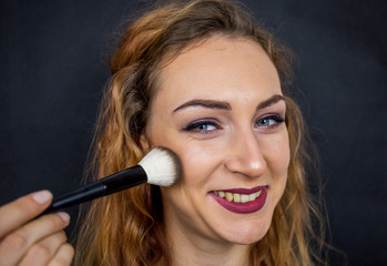 Fototapeta premium Portrait, beautiful girl, make-up, with smile posing on black background, makeup, powder, eye shadow, mascara, lipstick, eyeshadow