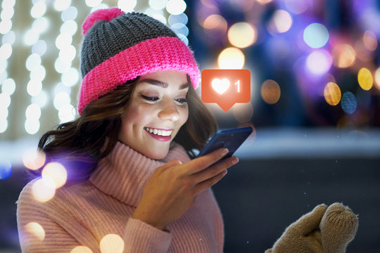 Young beautiful woman using her mobile phone in the city at night.