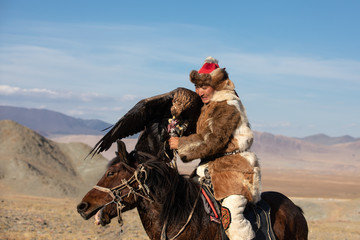 Eagle hunter struggling with his golden eagle on horseback. Ulgii, Mongolia.