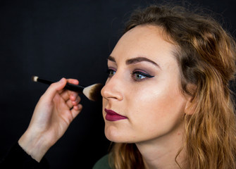 Obraz premium Portrait, beautiful girl, make-up, with smile posing on black background, makeup, powder, eye shadow, mascara, lipstick, eyeshadow