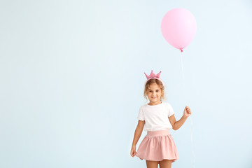 Little girl with balloon on color background