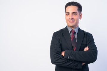 Portrait of happy Persian businessman in suit smiling with arms crossed
