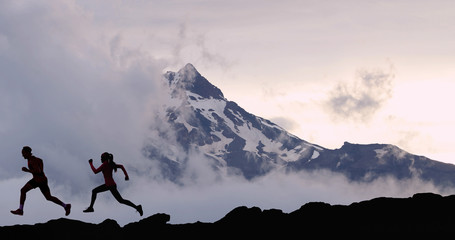Running fit athletes people trail running with mountain summit background. Man and woman...