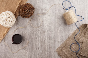 twine and two decorative balls, burlap and coffee mug on light gray wooden background.