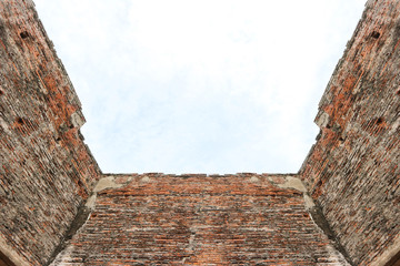 Dirty old weathered Brick building wall with clear sky background.