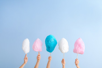 Female hands with different cotton candy on light background