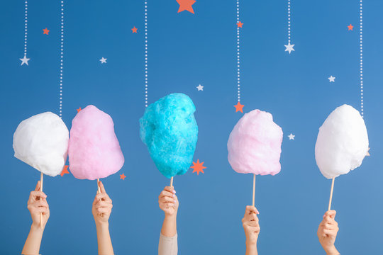 Female hands with different cotton candy on color background