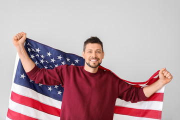 Handsome man with USA flag on light background. Memorial Day celebration