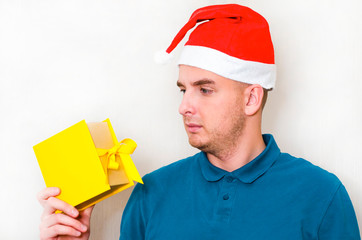 young handsome man with surprise looks at the box with a gift. guy holds a strange present in his...