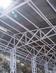 Fototapeta premium Low angle shot of a tin shed with iron frames and beautiful sun flares from top
