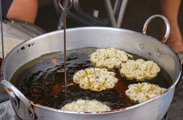 Thai traditional street snack food frying on hot oil pan.