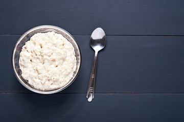 porridge in glass bowl with spoon on dark background