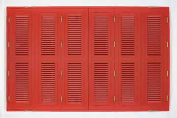 Vintage red wood panel window door on white cement wall background.