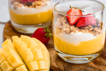 macro image of a glass with a dessert of mango, strawberry, cereal and ricotta