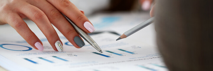 Female arm holding silver pen point in financial graph
