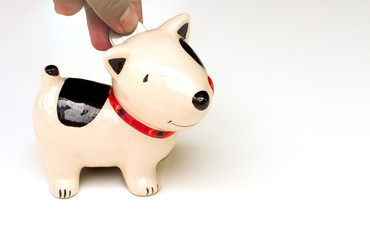Saving, male hand putting a coin into piggy bank.