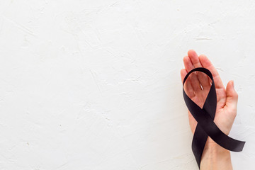 Disease control concept. Black ribbon in hands on white background top view copy space