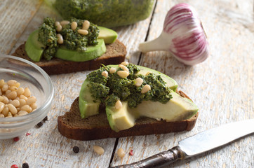Sandwich with pesto sauce and avocado on a wooden board