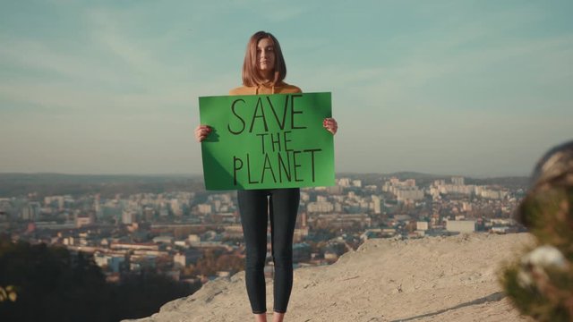Shot of woman activist holding encouraging green poster Save the Planet standing background beautiful view nature environmental community earth eco environment outdoor recycle trash waste slow motion