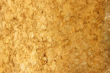 Thai ancient buddha statue back which decorating by small golden paper on surface skin wall background.