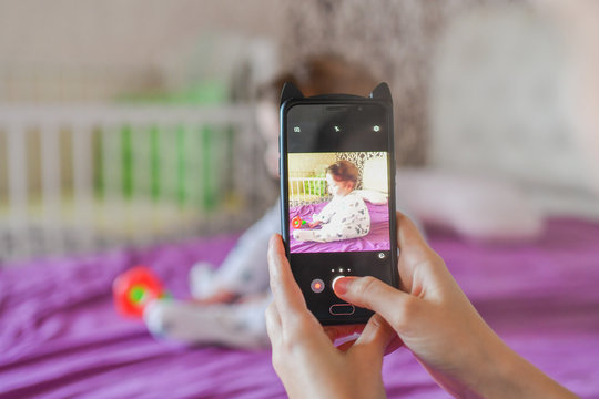 mom photographs her baby on the phone. Mother takes a photo of her newborn baby on a smartphone. Family memories.