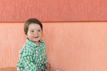 happy baby on a coral background. Head and shoulders portrait of cute blue-eyed baby girl looking at camera and laughing on a coral color