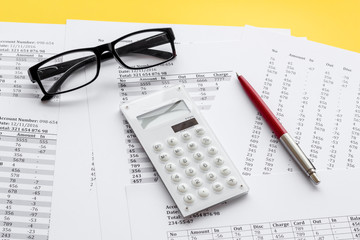 Naklejka na ściany i meble Taxes calculation concept. Financial documents, calculator, glasses on yellow background