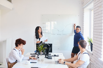 Obraz premium African woman in blue office suit stand showing and speaking about scheme charts, business ideas, business upgrade . Listeners look at coach