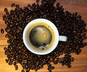 Coffee mugs and coffee beans resting on a brown wooden table.