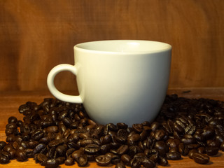 Coffee mugs and coffee beans resting on a brown wooden table.
