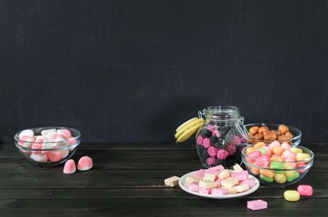 multi-colored candies in a plate, bank and bowls with copy space