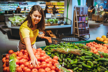 woman choosing red tomatoes from store shelf grocery shopping