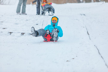 young woman sliding down by snowed hill