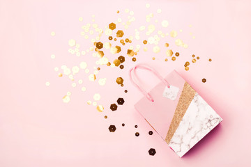 Geometric paper shopping bag and trendy hexagonal sparkles on pink background. Holiday sale concept