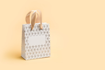 Paper shopping bag on beige background. Holiday sale concept in monochrome tones