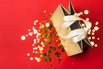 Gold Paper shopping bag and trendy hexagonal sparkles on red background. Holiday sale concept